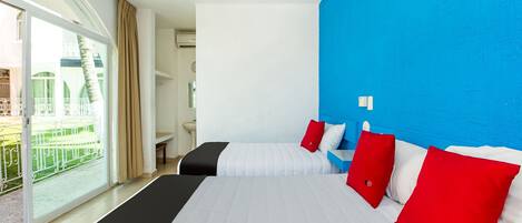 Quarto de hotel com uma cama grande, um ventilador de teto, banheiro e vista para uma piscina e um edifício.
