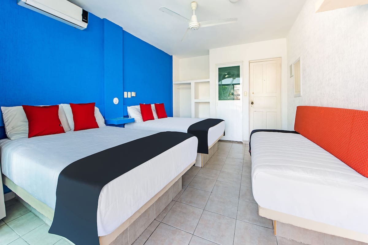 Una habitación de hotel con dos camas, un ventilador de techo y una puerta blanca.