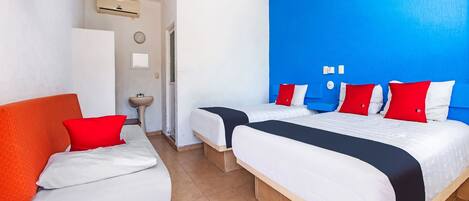 A hotel room with two beds, a sink, and a ceiling fan.