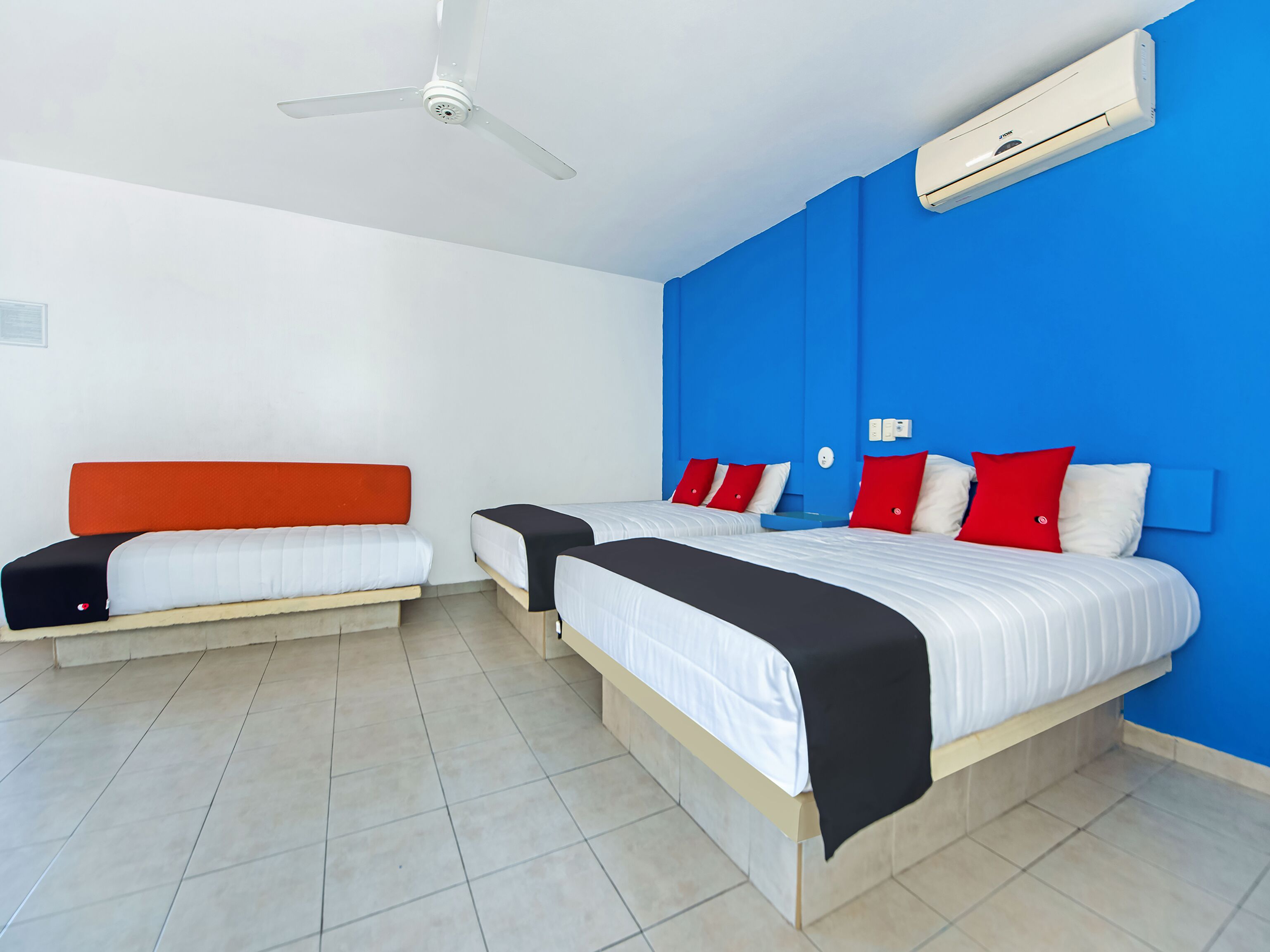A hotel room with two beds, a ceiling fan, and an air conditioning unit.