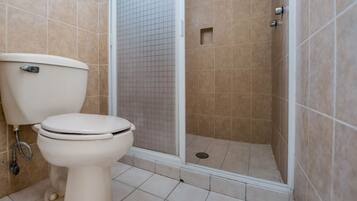 Un baño con inodoro, ducha y paredes de azulejos.