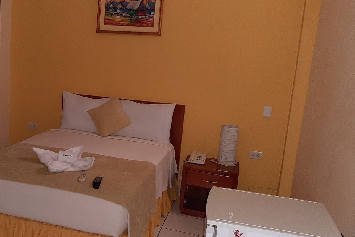 Une chambre d’hôtel avec un lit, une table de chevet, une lampe et un tableau au mur.