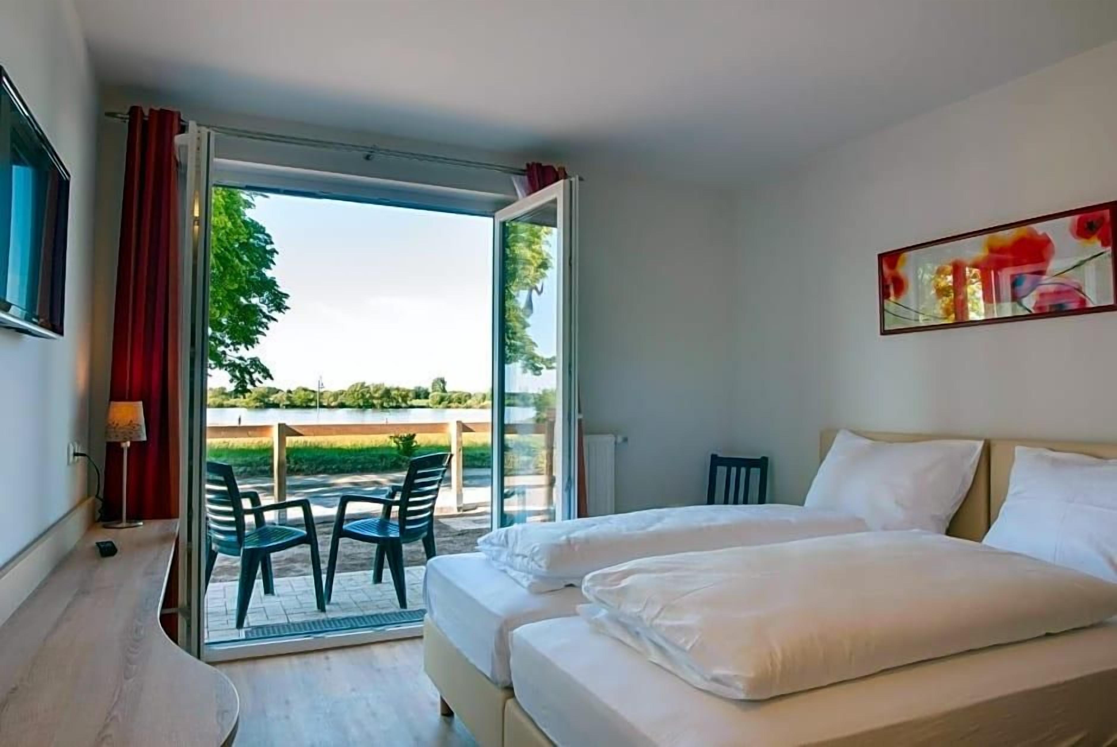 A hotel room with a bed, a desk, and a chair. There is a window with a view of the outdoors.
