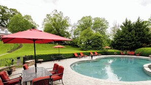 A pool area with red umbrellas, lounge chairs, and a tiled patio. - The Inn at Whitewing Farm (West Chester)