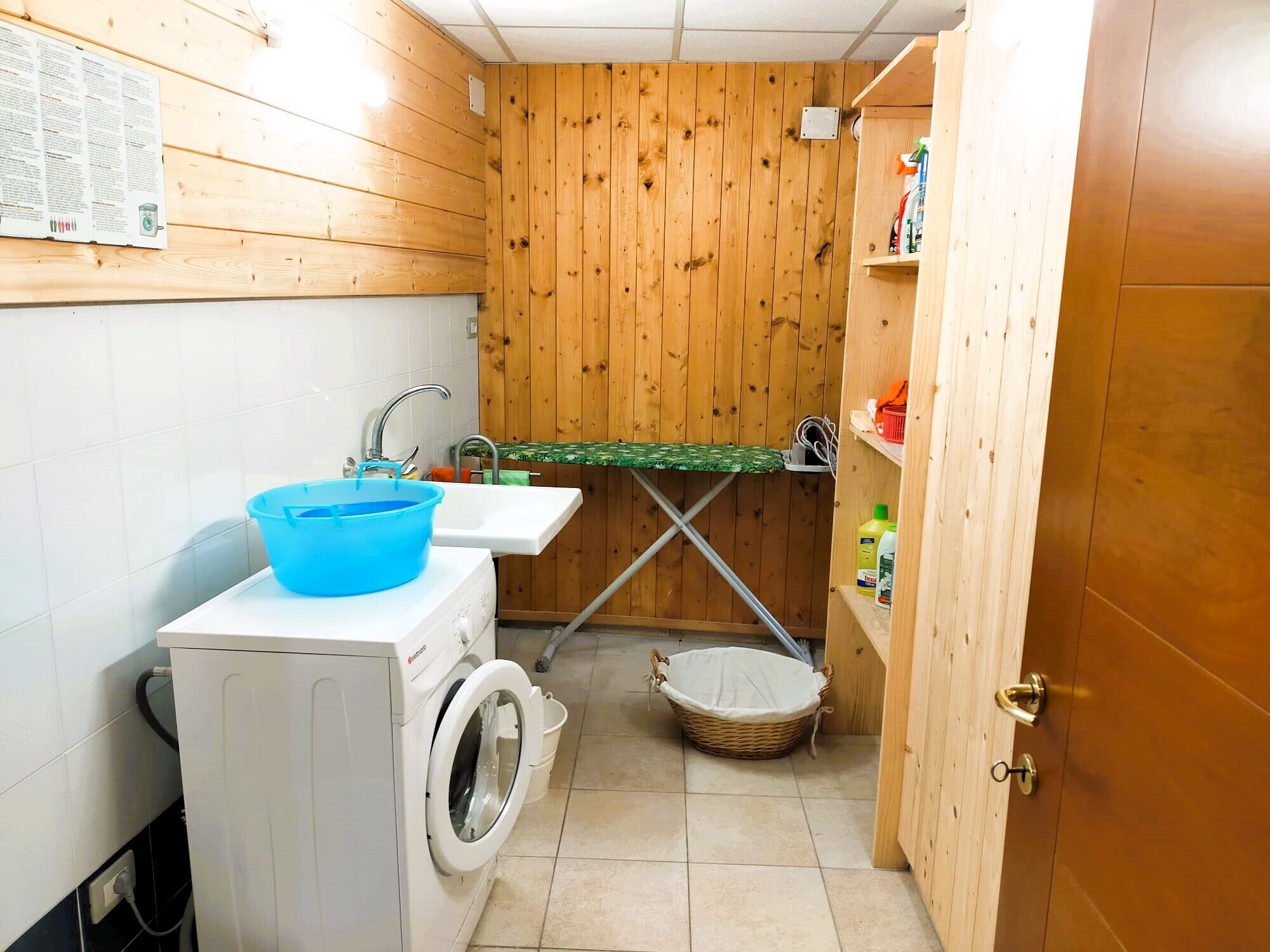 A compact laundry room with a washing machine, a sink, and a drying rack.