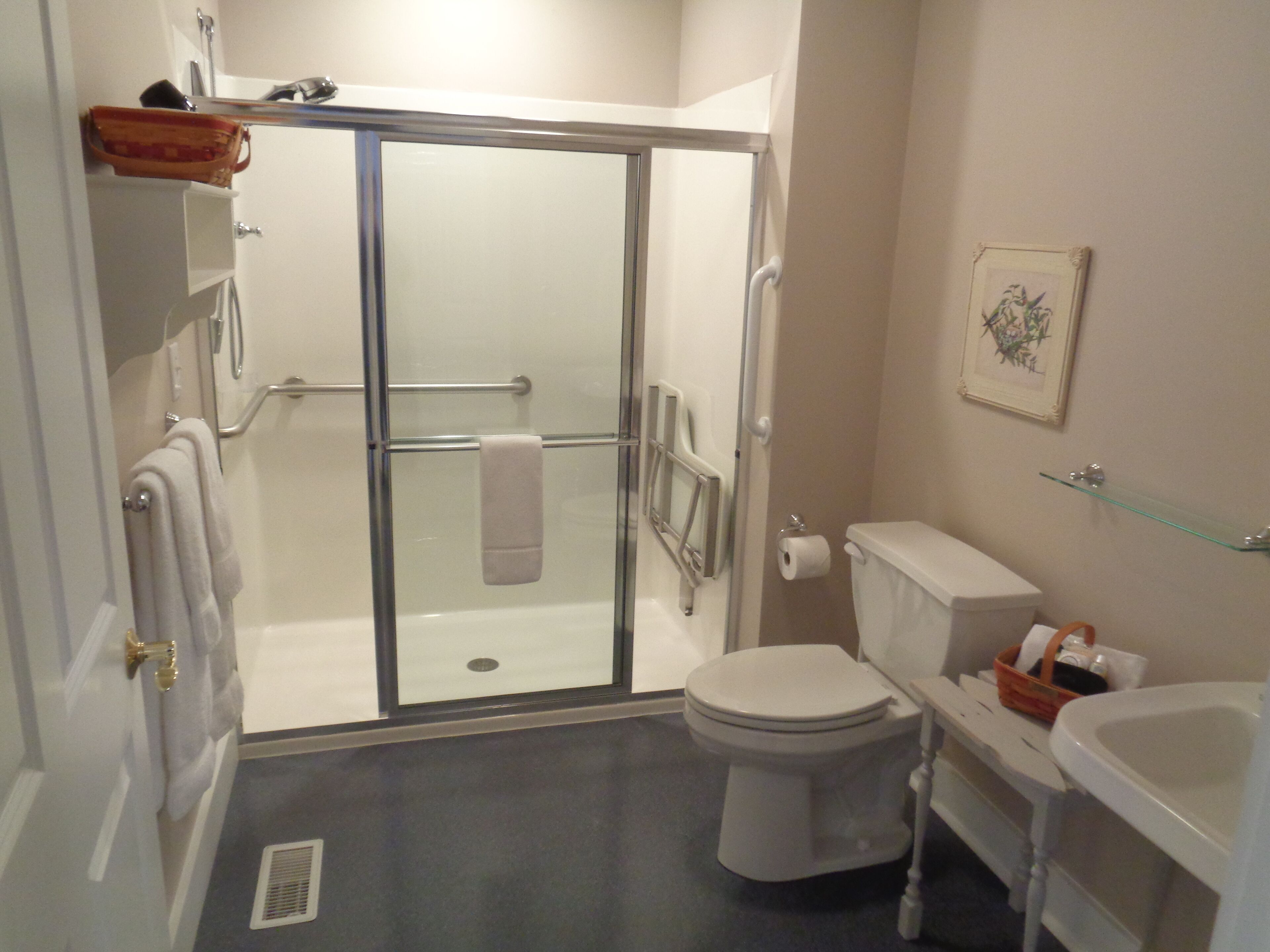 Une salle de bain avec une douche à parois de verre, des toilettes, un lavabo et un porte-serviettes.