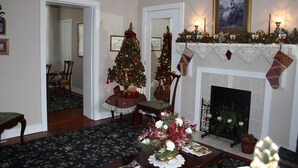 Een woonkamer met een open haard, een kerstboom en feestdecoraties.