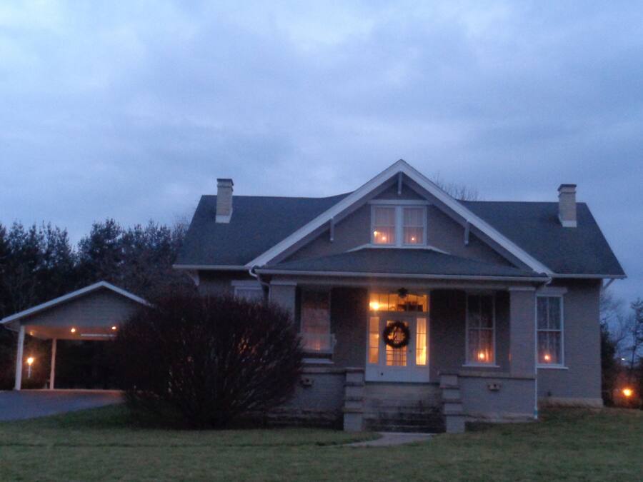 A two-story house with a front porch, a visible garage, and a wreath on the door.
