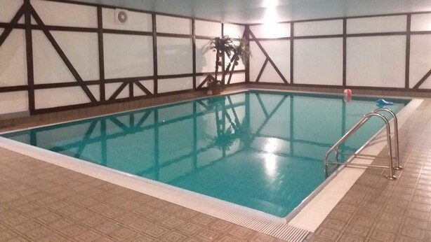 An indoor swimming pool with clear blue water, surrounded by a tiled floor and walls with a geometric pattern. - Gasthaus Linde (Eberbach)