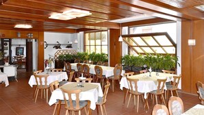 A restaurant with wooden ceiling beams, white tablecloths, and wooden chairs. - Gasthaus Linde (Eberbach)