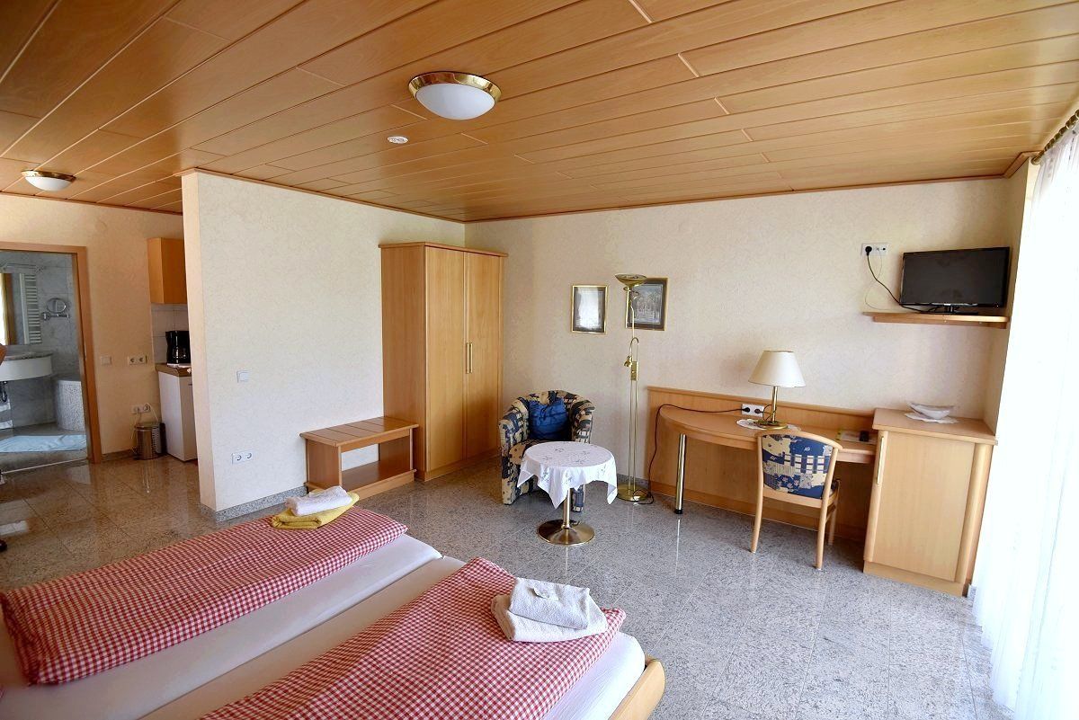 A hotel room with two beds, a desk, a chair, a television, and a small table.