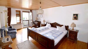 A bedroom with a wooden bed, bedside tables, a desk, a chair, and a window with curtains. - Gasthaus Linde (Eberbach)