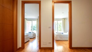 Une chambre d’hôtel avec un plancher en bois, un lit et une vue sur l’extérieur, grâce à une porte ouverte.