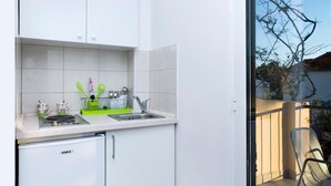 Uma cozinha compacta com armários brancos, máquina de lavar louça embutida e um pequeno balcão.