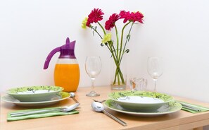 A table set with plates, a pitcher of orange juice, and a vase with flowers. - Apartments Denise Podgora (Podgora)