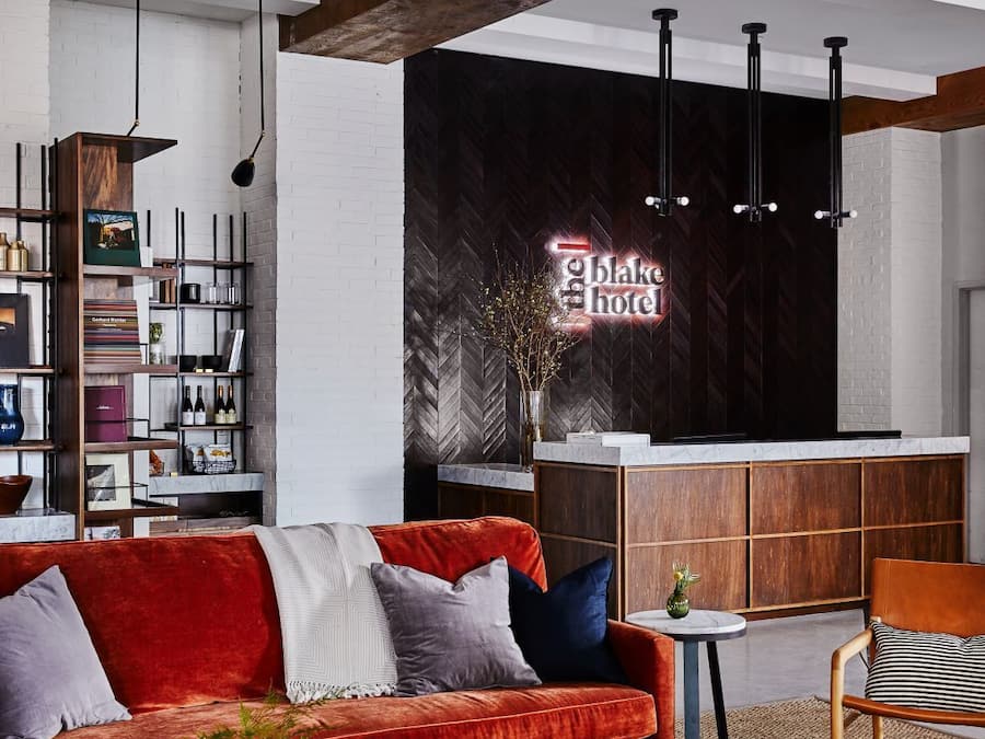 A modern hotel lobby with a red sofa, a coffee table, and a reception desk.