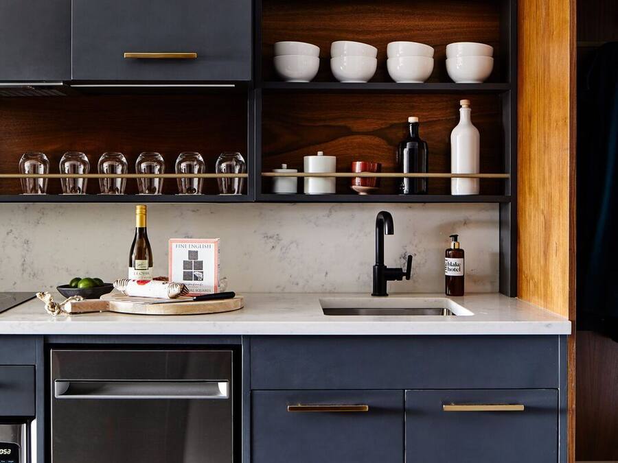 A modern kitchen with dark cabinetry, a marble countertop, and a stainless steel dishwasher.