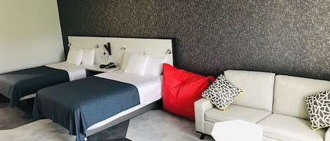 Et moderne hotelværelse med en stor seng, en sofa og et lille hvidt bord.