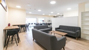 A modern lounge area with sofas, tables, and chairs. - Hobson Lodge - Hostel (Auckland)