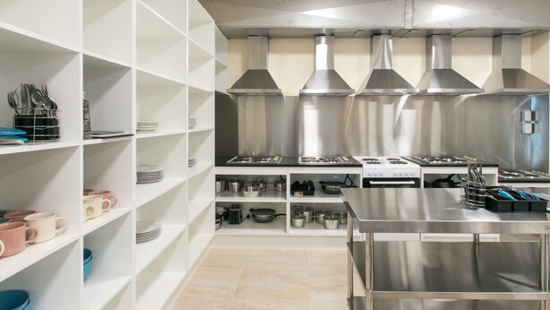 A modern kitchen with stainless steel appliances, white shelving, and a tiled floor. - Hobson Lodge - Hostel (Auckland)