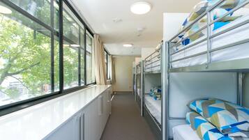 A narrow corridor with bunk beds on one side and a window on the other.