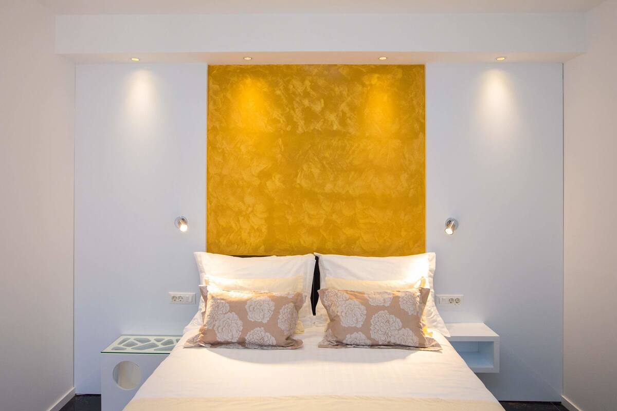 A modern bedroom with a large bed, two bedside tables, and a unique textured wall.