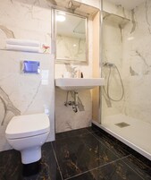 A bathroom with a toilet, sink, and shower.