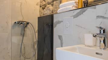 A modern bathroom with a glass-enclosed shower, a white toilet, and a marble sink.