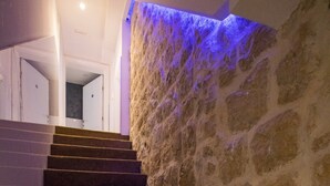 Una escalera con paredes de piedra y una pared iluminada en azul al final.