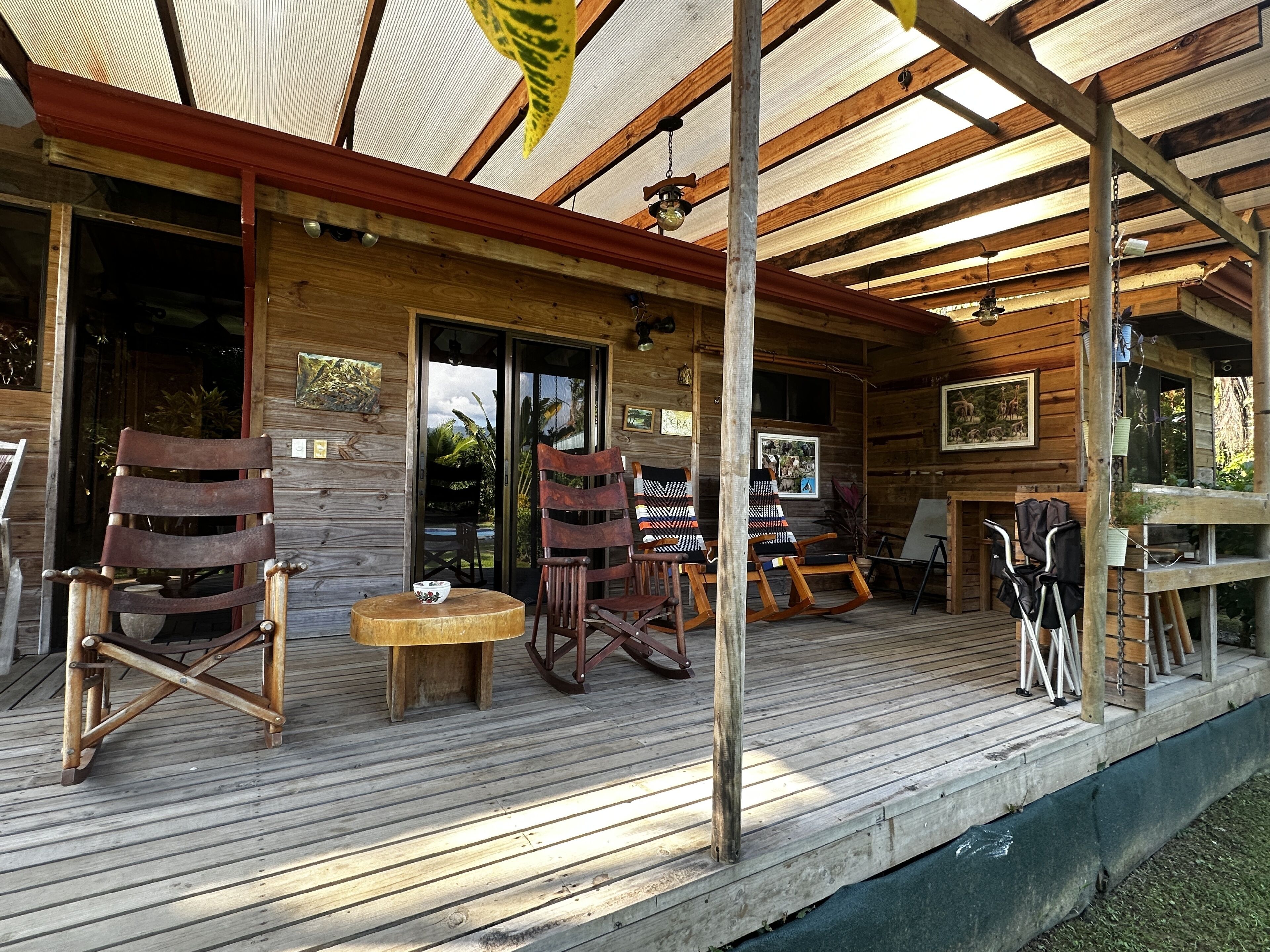 A wooden deck with outdoor seating, including chairs and a table, and a covered area with a ceiling fan.
