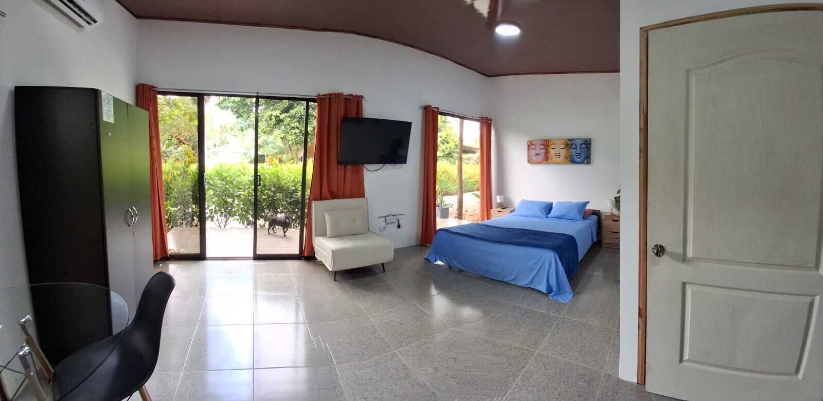 A room with a bed, a TV, a chair, and a door.