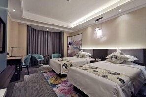 Ein Hotelzimmer mit zwei Betten, einem Schreibtisch, einem Stuhl und einem großen Fenster mit Vorhängen.