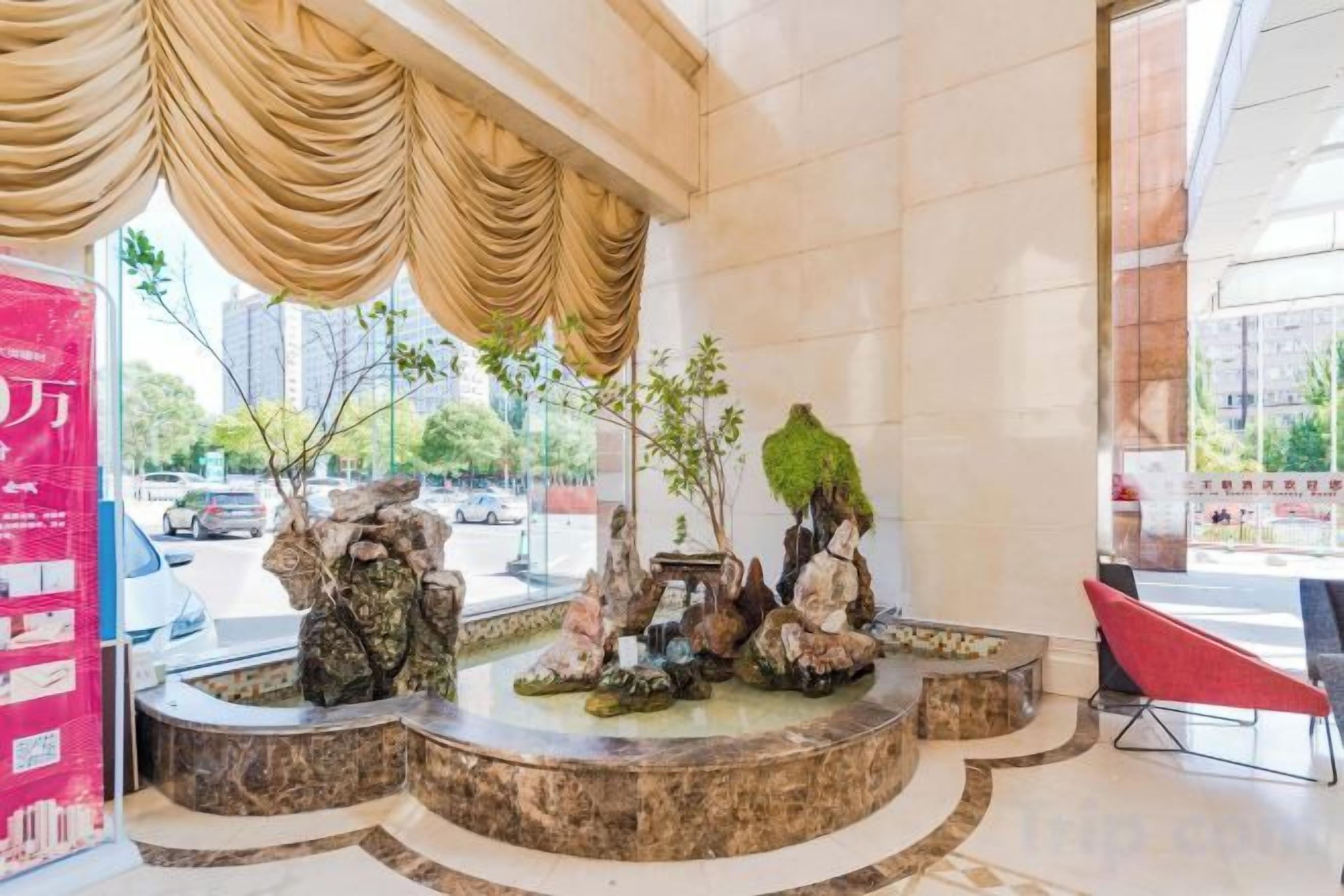 A lobby with a marble floor, a fountain, and a red chair.