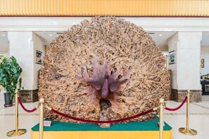 Eine große, detaillierte Skulptur in einer Eingangshalle mit grünem Teppich und roten Absperrseilen.