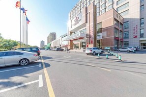 A multi-story hotel with a modern facade, a large entrance, and a parking lot with cars.