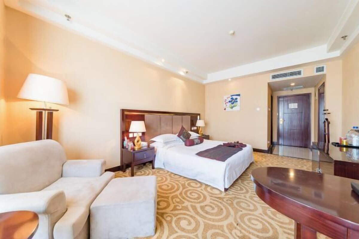 Habitació d'hotel amb llit, sofà, escriptori i làmpada.