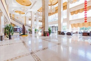 Un vestíbulo espacioso con techo alto, ventanas amplias y una escalera central.