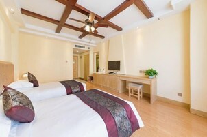 Habitación de hotel con dos camas, un escritorio, un televisor y un ventilador de techo.