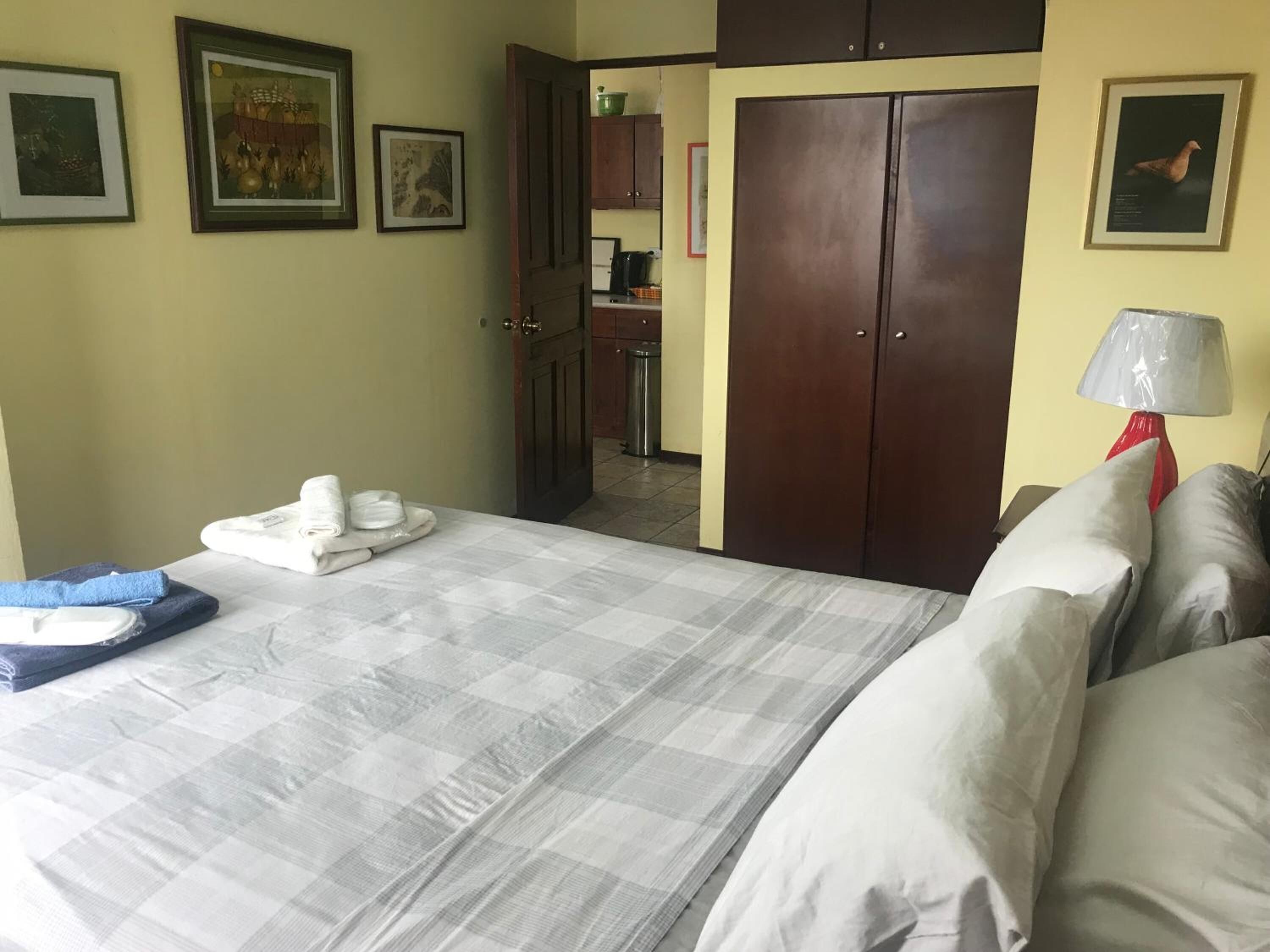 A hotel room with a bed, a bathroom, and a kitchenette.