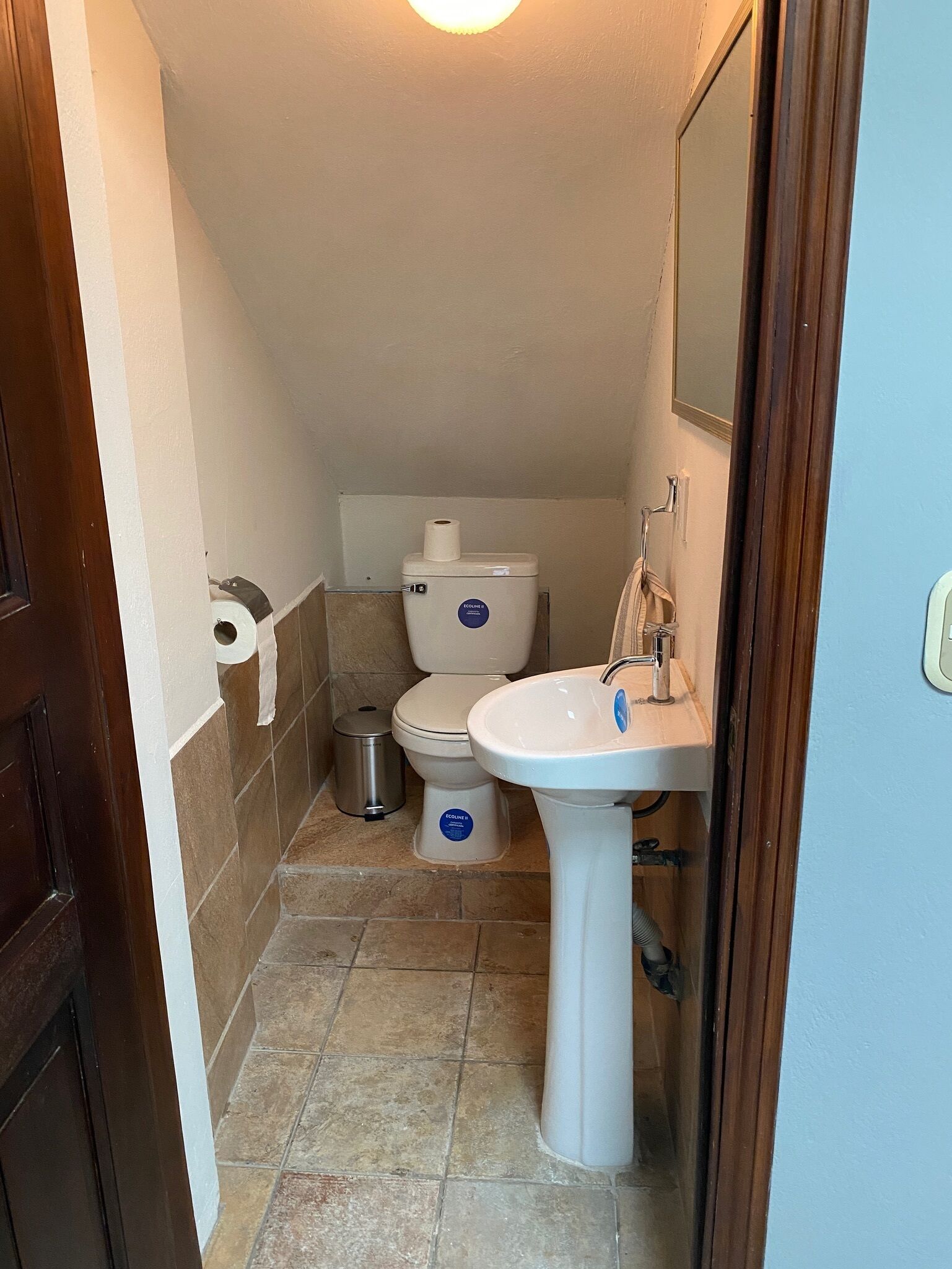 Een kleine badkamer met toilet, wastafel en een prullenbak.