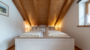 Un dormitorio con techo de madera, una cama con sábanas blancas y dos lámparas de noche.