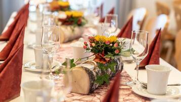 A dining table set with white plates, clear glasses, and red napkins.