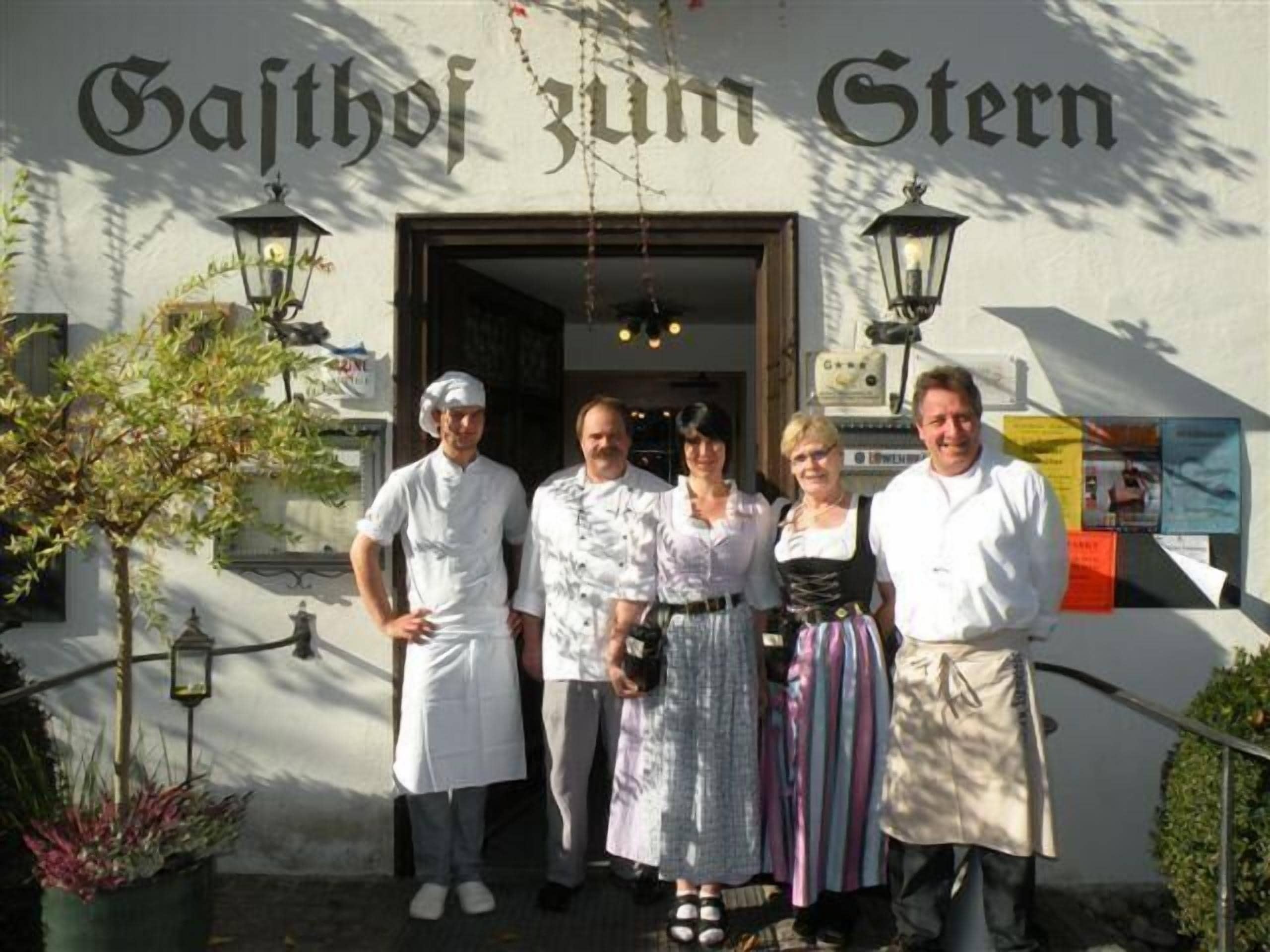 A group of people standing in front of a building with a sign that reads "Gästhof zum Stern".