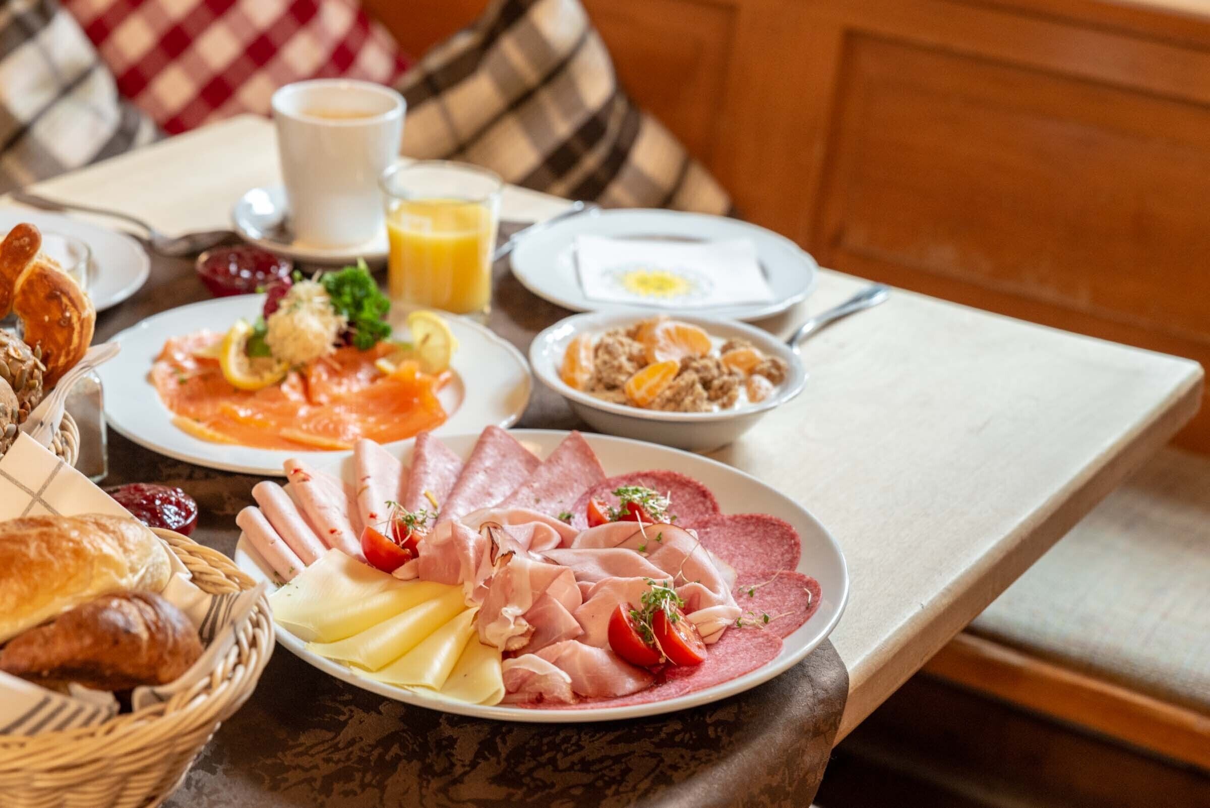 Een ontbijttafel met diverse producten zoals gebak, kaas, ham en eieren.