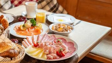 Een ontbijttafel met diverse producten zoals gebak, kaas, ham en eieren.