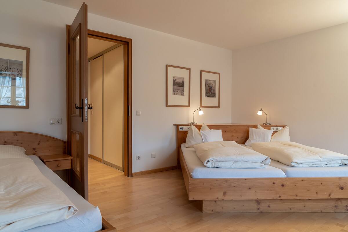 Un dormitorio con una cama de madera, una mesita de noche y una puerta que da a otra habitación.