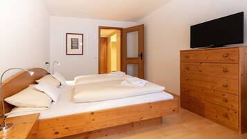 A bedroom with a wooden bed, a dresser, a television, and a framed picture on the wall.