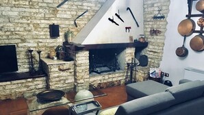 A rustic living room with a stone fireplace, a television, and a modern sofa. - B&B Il Cedro (Foligno)
