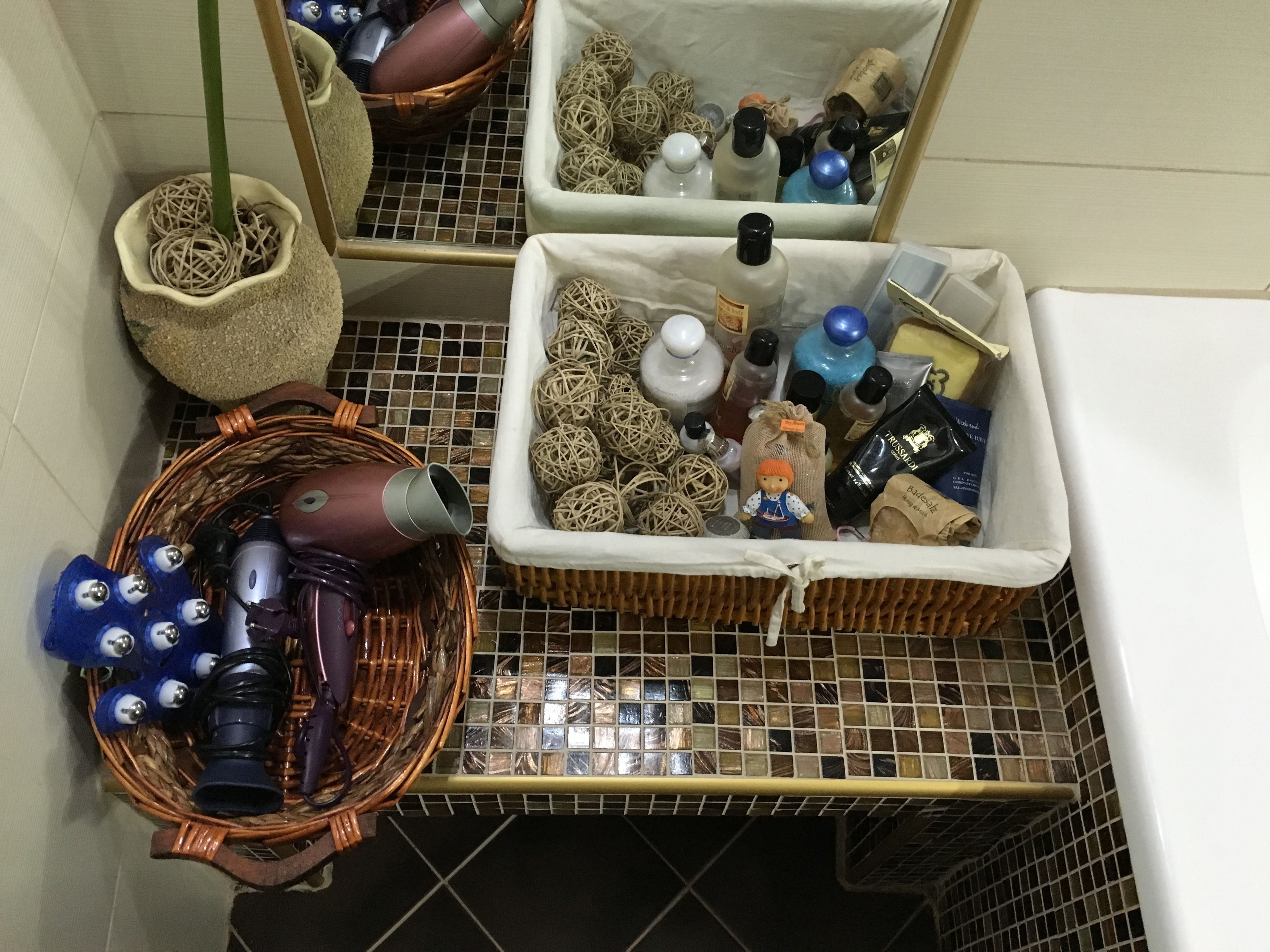 A bathroom with a tiled floor, a wicker basket, and a wicker basket with a plant.