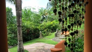 A garden with a stone pathway, a palm tree, and a seating area with a stone planter. - Madrugada Residencial (Las Terrenas)
